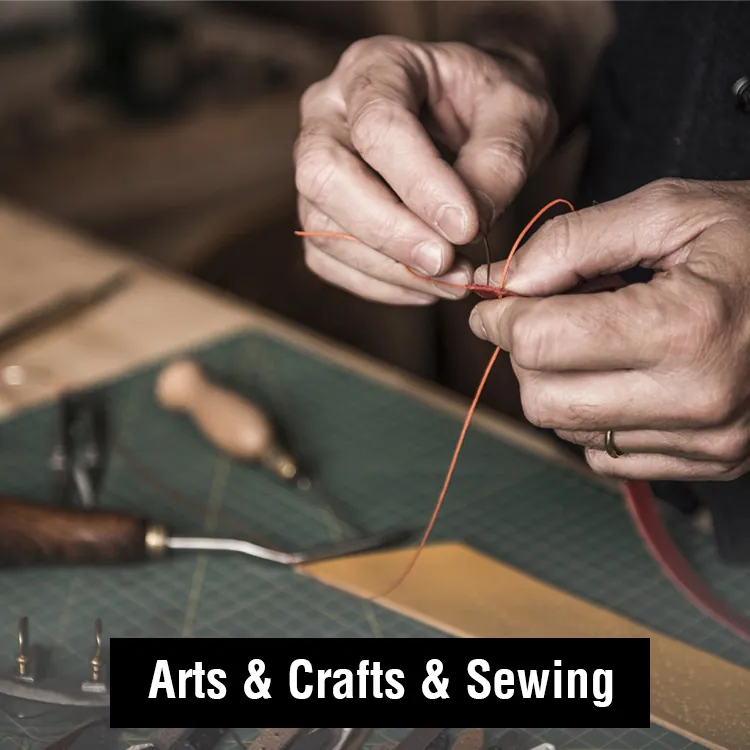 Hands threading a needle over a leather workbench